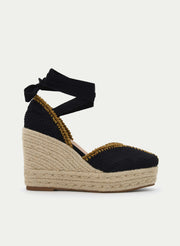 Black braided jute wedge sandals with ankle straps.