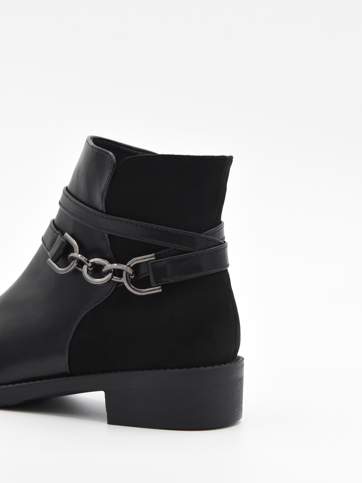 Botín negro de mujer en material sintético efecto piel, con detalle de cadena metálica lateral y tacón bajo ancho.