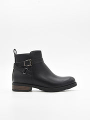 Botín de mujer en material sintético negro efecto piel, con hebilla lateral metálica y tacón bajo ancho con detalle de madera.